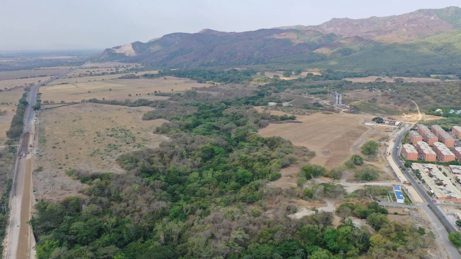Vista aérea del terreno del proyecto, rodeado de bosque y montañas